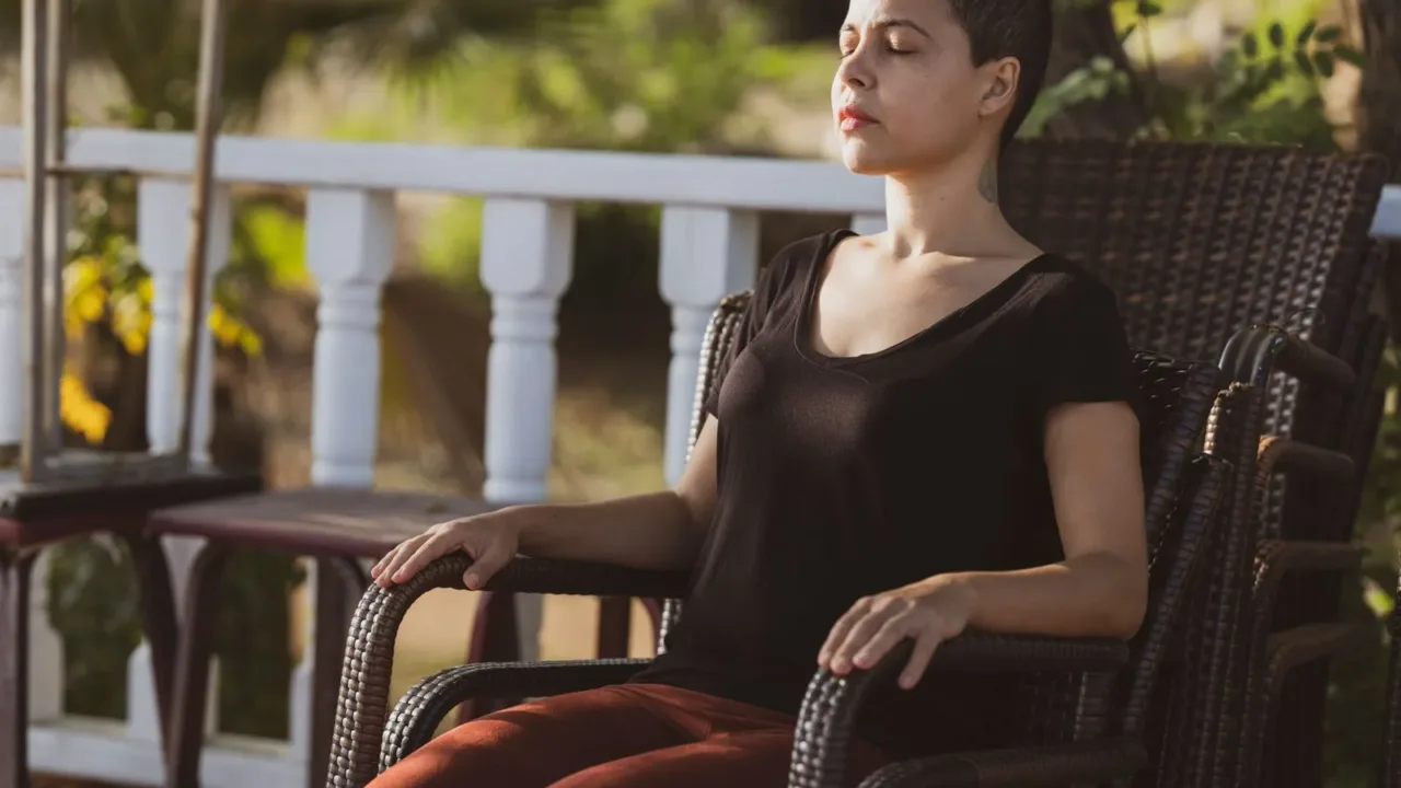 Persona sentada en una silla con los ojos cerrados practicando una técnica de respiración y mindfulness durante una pausa activa.