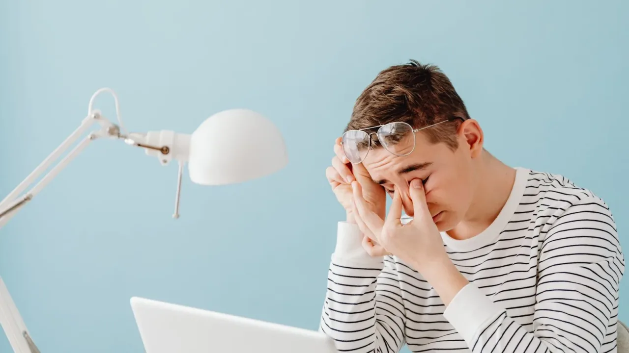 Hombre apartando la mirada de la pantalla y frotándose los ojos para descansar la vista, como parte de una pausa activa.