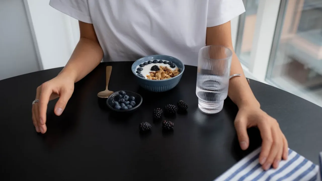 Persona comiendo yogur con frutas, ilustrando probióticos y triptófano para la serotonina y el enfoque.