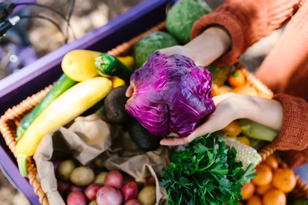 Persona sosteniendo verduras frescas en un mercado, representando alimentos accesibles para la claridad mental.